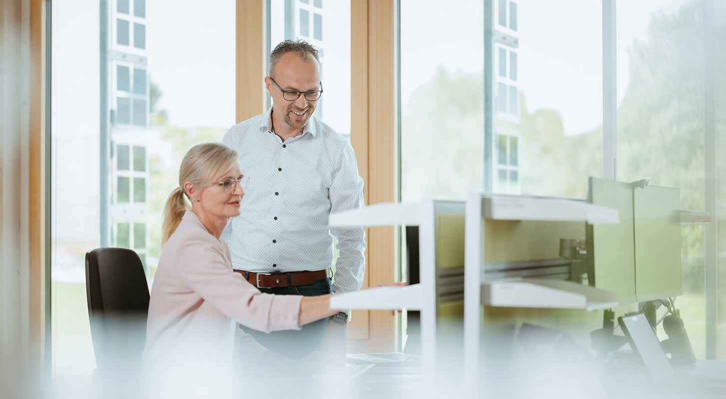 A man and woman stand before a computer, analyzing municipal energy data and consumption trends for various sectors.